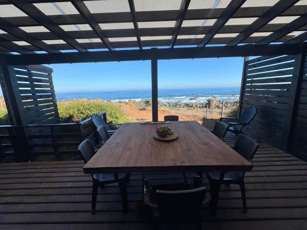 a wooden table on a deck with a view of the ocean at Almar House in Guaquen
