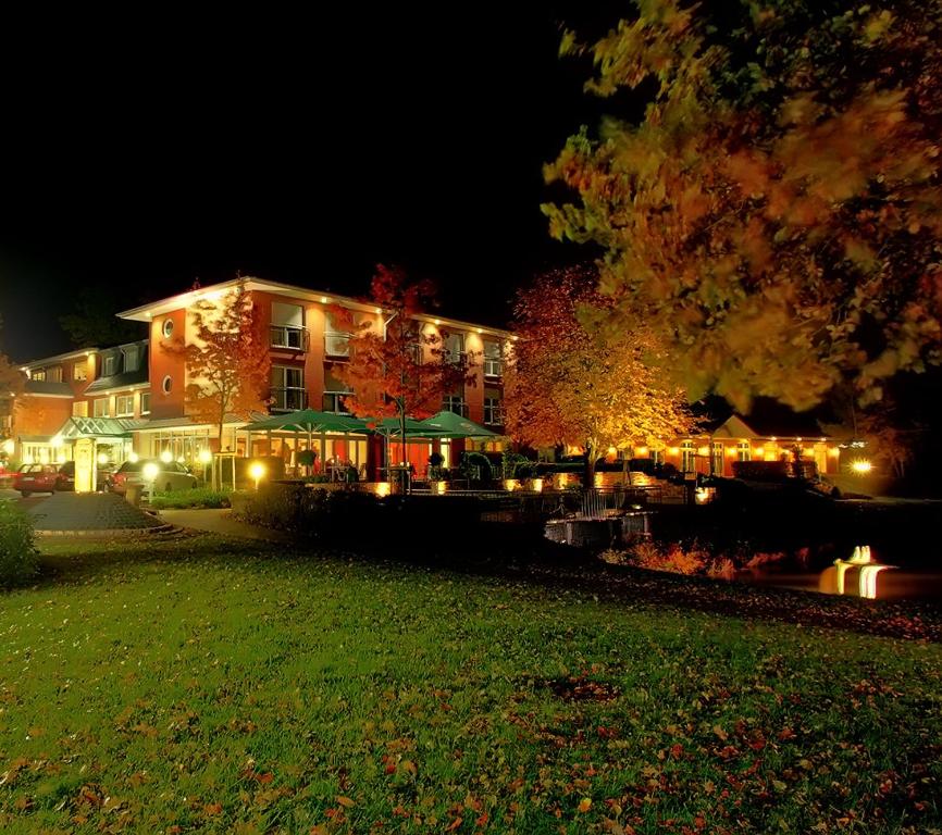 a large building with lights in a yard at night at Hotel Driland in Gronau