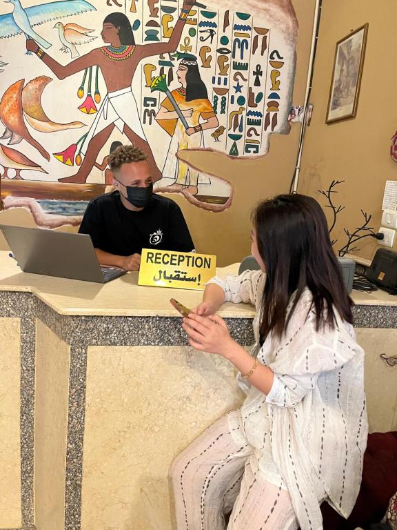 eine Frau sitzt mit einem Mann mit einem Schild an einem Tisch in der Unterkunft KR Elite Hotel in Luxor