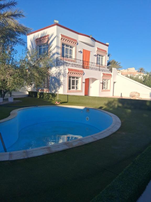 a villa with a swimming pool in front of a house at Ksour tataouine in Qaşr al Muqābilah
