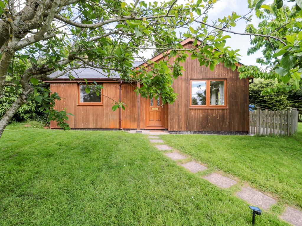 a house with a wooden door in a yard at Orchard Cottage in Ledbury
