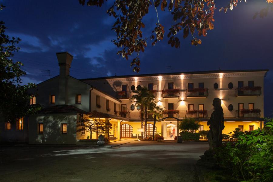 un grand bâtiment avec une statue devant lui la nuit dans l'établissement Hotel Antico Mulino, à Scorzè