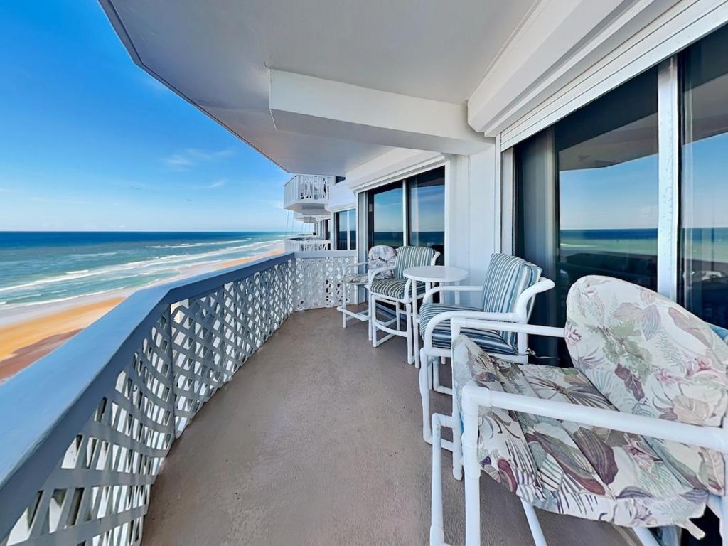 a balcony with chairs and tables on the beach at Oceanside Retreat 804 in Ormond Beach