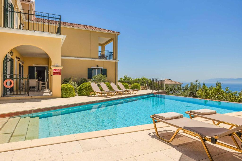 a swimming pool in a villa with chairs and a house at Villa Mihas in Vlachata