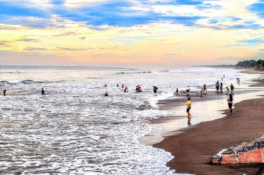 a group of people walking in the water on the beach at Poneloya Budget Accomodations in León