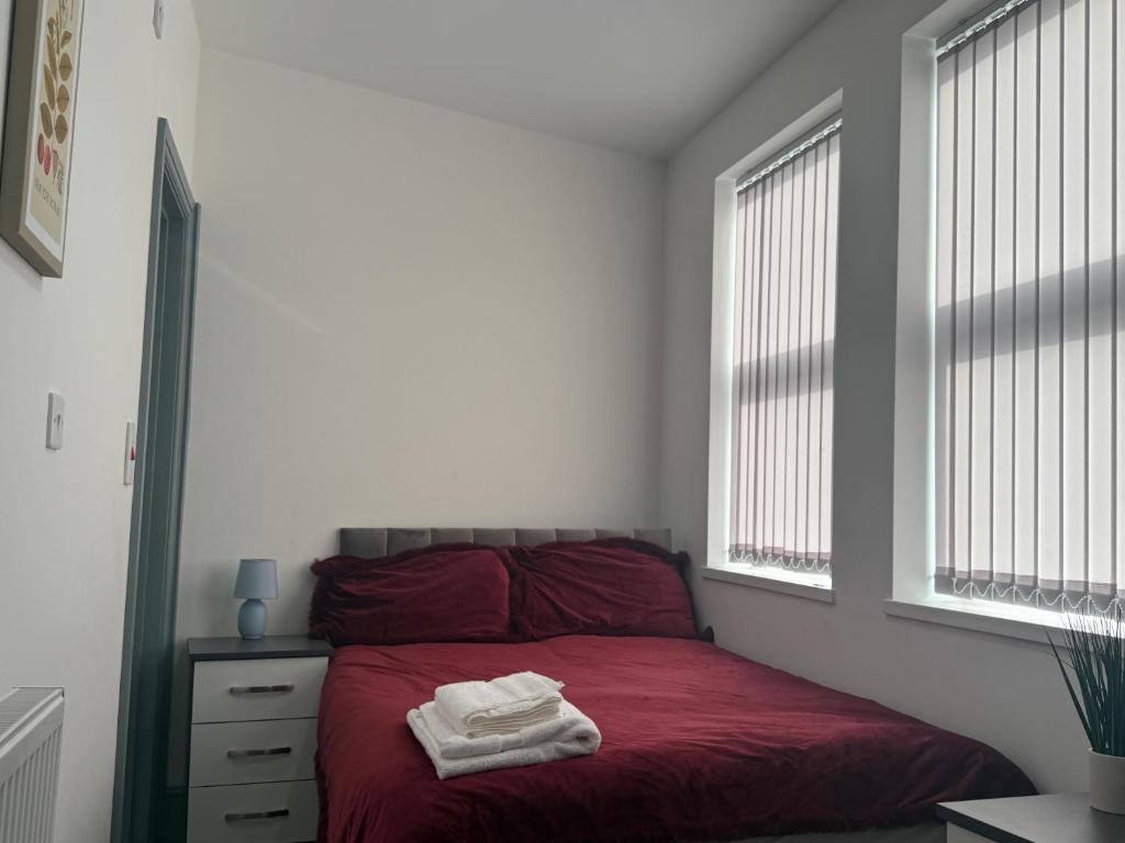 ein Schlafzimmer mit einem roten Bett, auf dem zwei Handtücher liegen in der Unterkunft PLUS Properties Dike 3 Ensuite in Stoke on Trent
