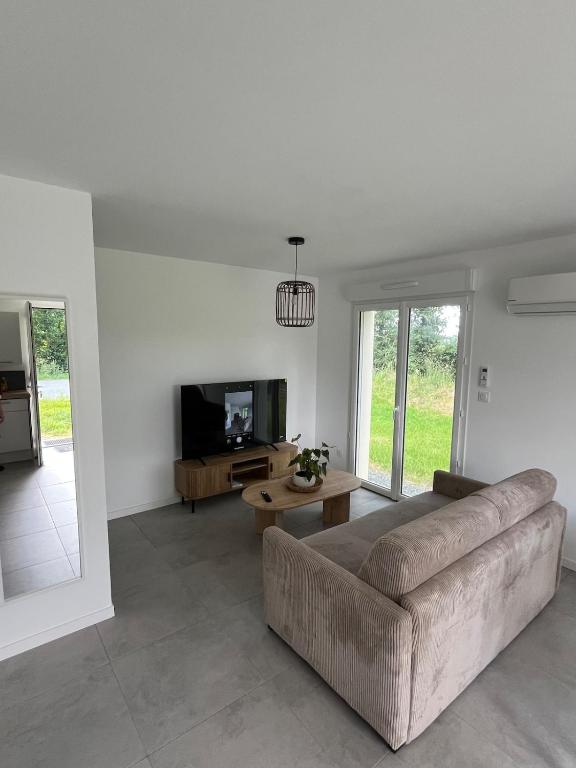 a living room with a couch and a tv at Cottage with garden in La Roche-sur-Yon
