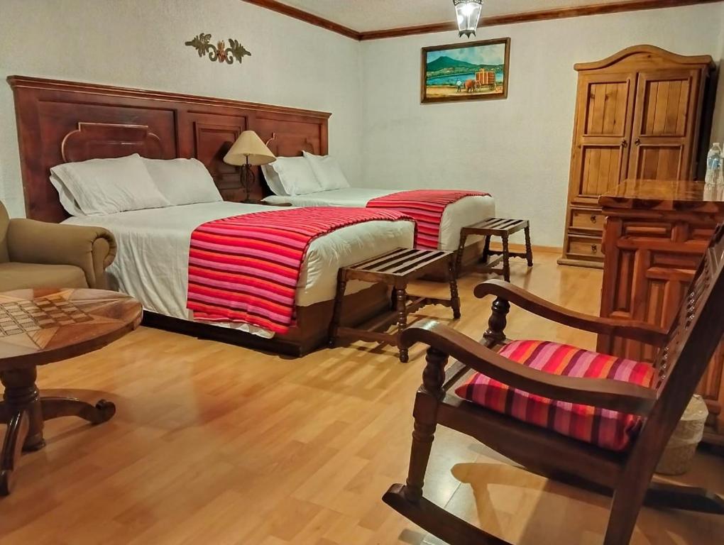 a bedroom with two beds and a chair and a table at Hotel Rincon de Josefa in Pátzcuaro