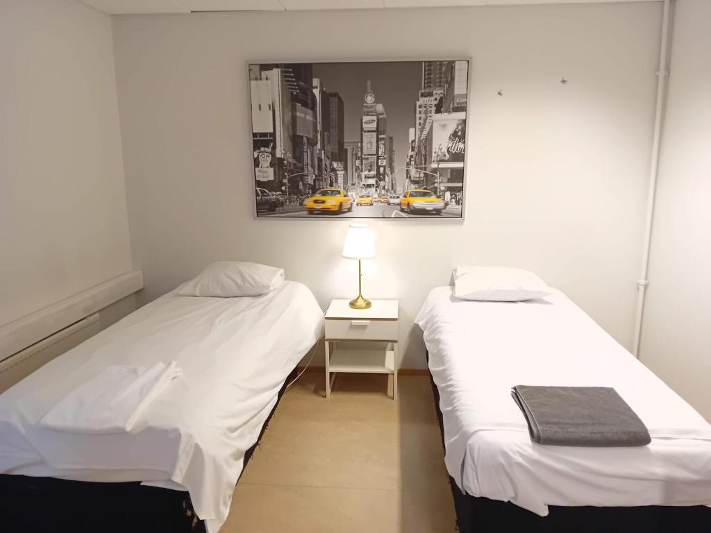 two beds in a room with a picture on the wall at Hostel Yöpöllö in Kouvola