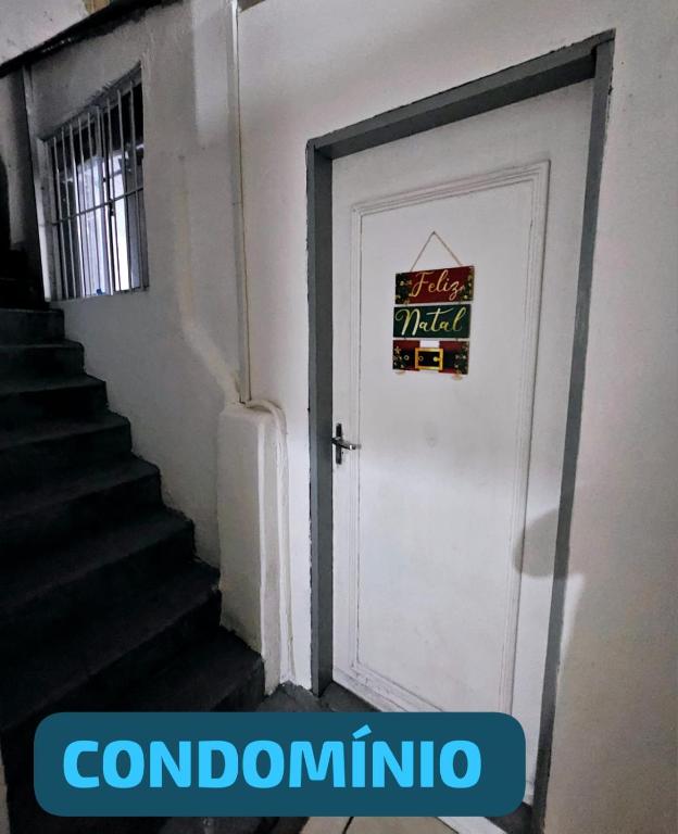 a white door with a sign on it next to a staircase at Condomínio top in São Paulo