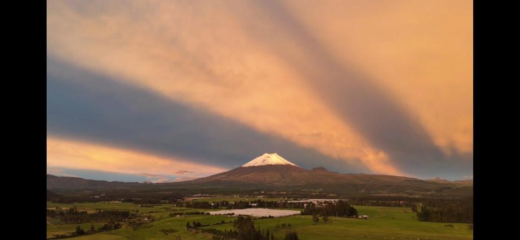 a mountain with a rainbow in the sky over a city at BaseCotopaxi Mini depart 5p free parking in Latacunga