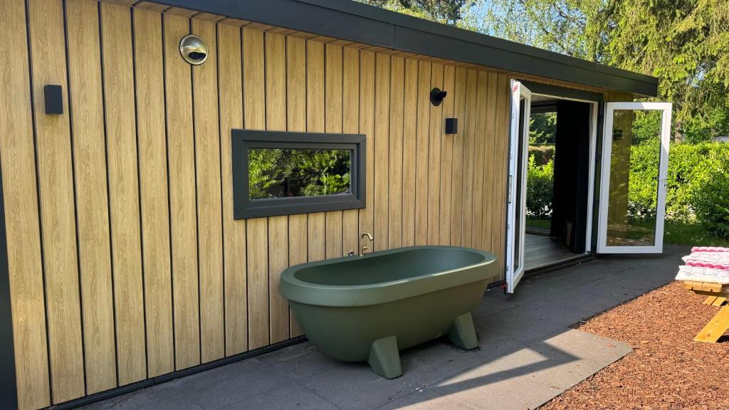 a green bath tub sitting outside of a house at Panterhuis Leo l Tiny House l Buitenbad, airco, speeltuin, bostuin in Epe