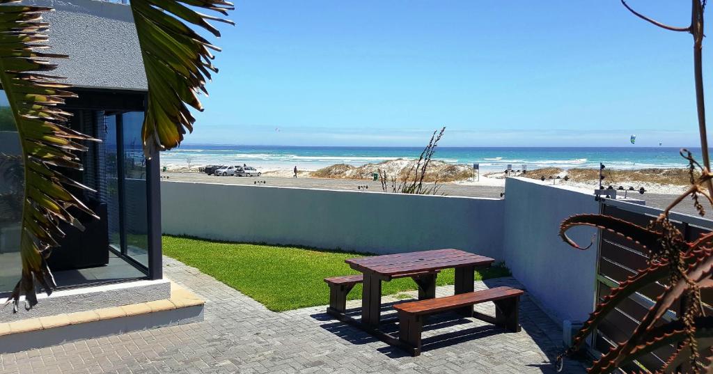 a wooden bench sitting on a patio near the beach at Beach Apartment Melkbosstrand in Melkbosstrand