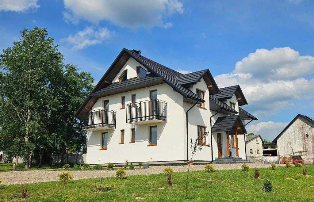 a large white house with a black roof at Noclegi Widokowa Przystań in Krajno Pierwsze