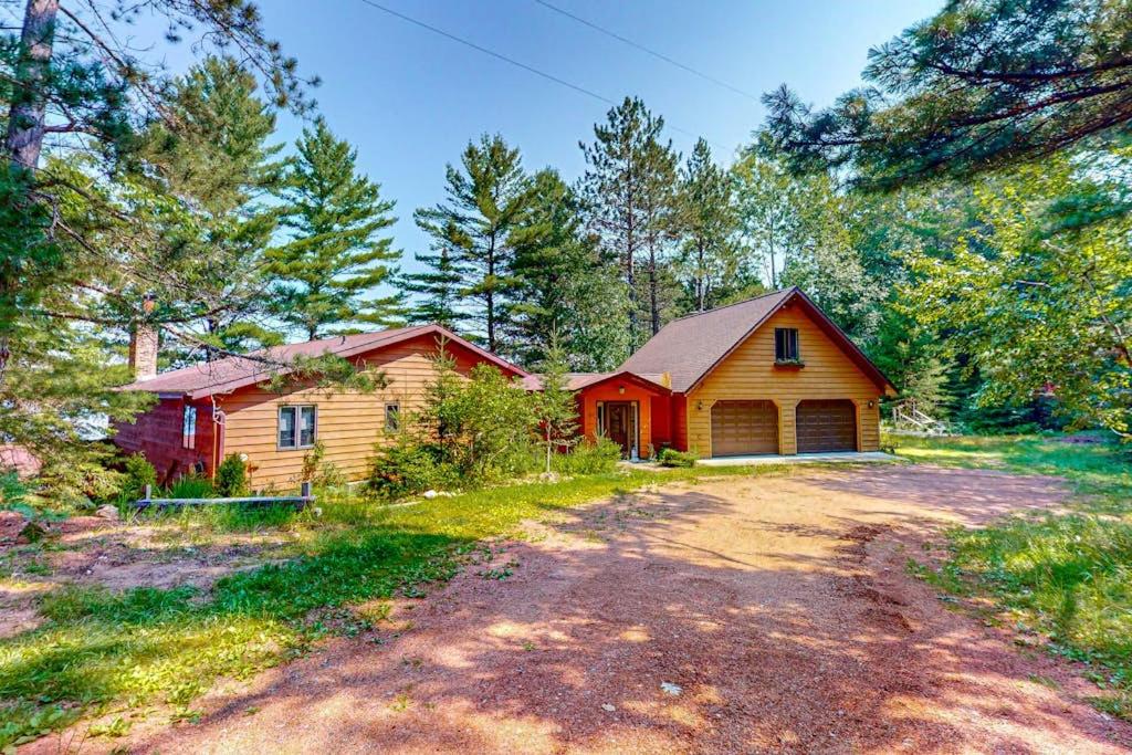 a house in the woods with a dirt road in front at Two Sisters Lakeside in Rhinelander