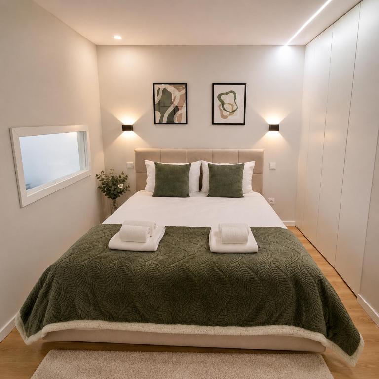 a bedroom with a large bed with two towels on it at Alameda Apartments 2 in Trofa