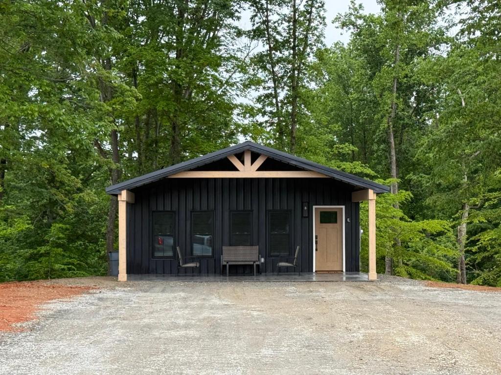 a black cabin with chairs in the woods at The Hideaway at Wolf Creek in Nancy