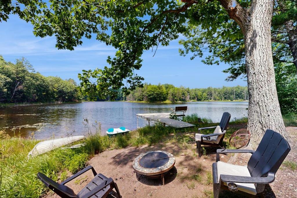 a group of chairs and a fire pit next to a lake at Blue Jay Cabin in Rhinelander