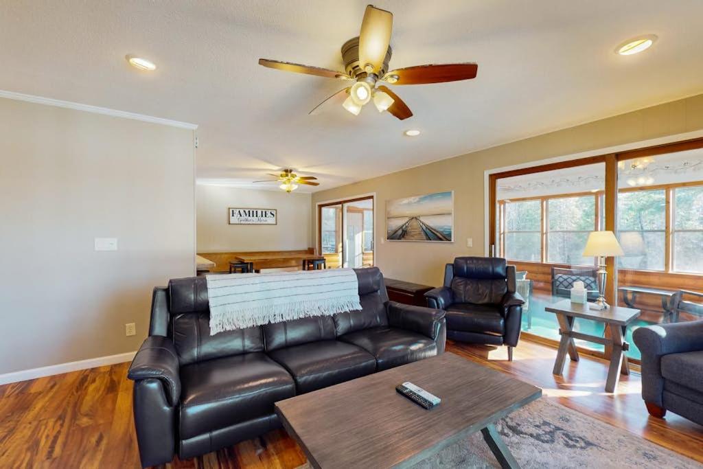 a living room with a leather couch and a ceiling fan at Dreams on the Lake in Tomahawk
