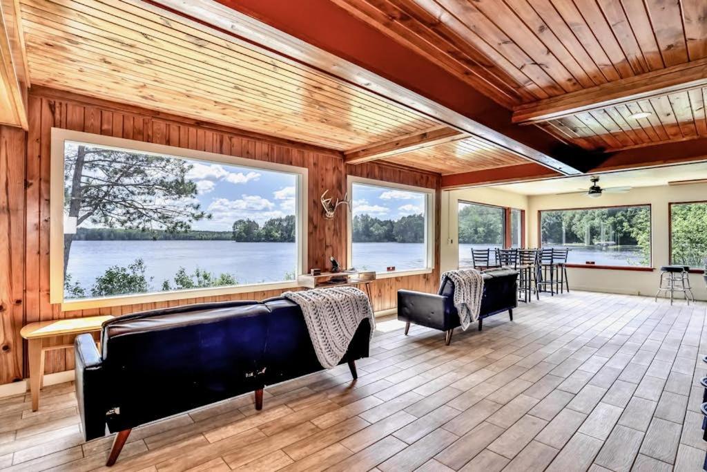 a large living room with windows and a table and chairs at Timber Lodge Retreat in Rhinelander