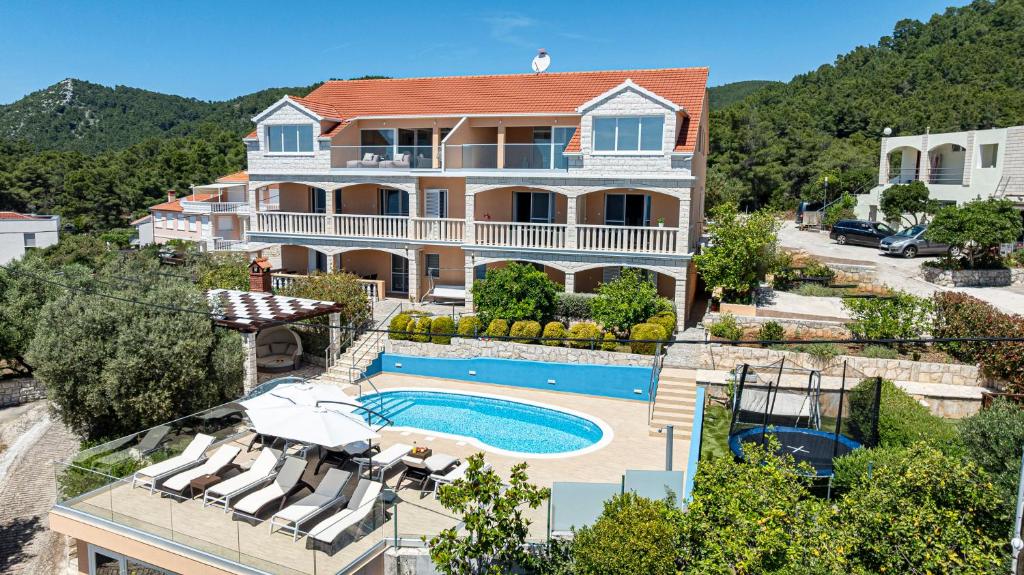 a large house with a swimming pool in front of it at Apartments Separovic in Prizba