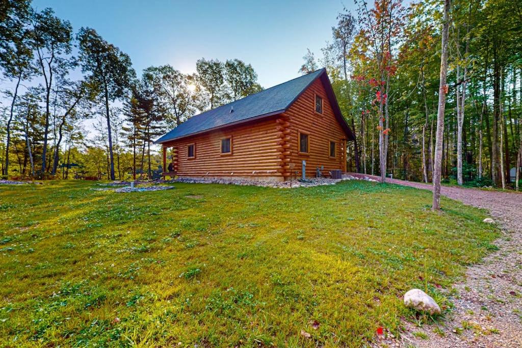 a log cabin in the middle of a grass field at Brown Bear Cabin in Tomahawk