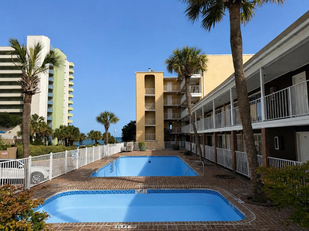 a swimming pool in front of a building with palm trees at Ocean 12 Beach Hotel in Myrtle Beach