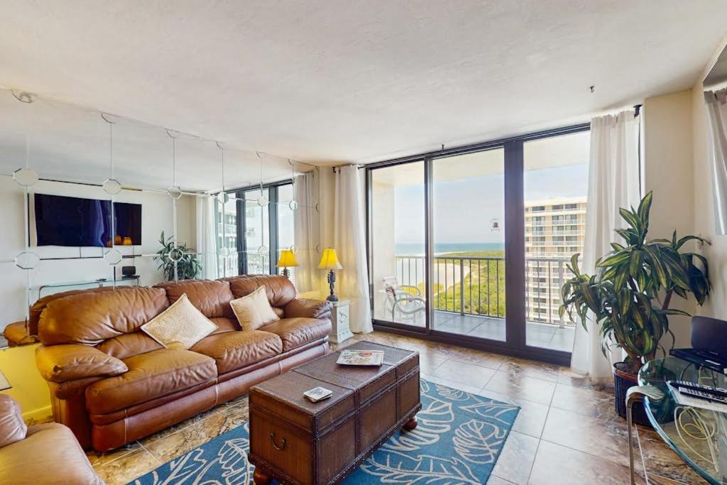 a living room with a leather couch and a balcony at The Breezy Perch in Marco Island