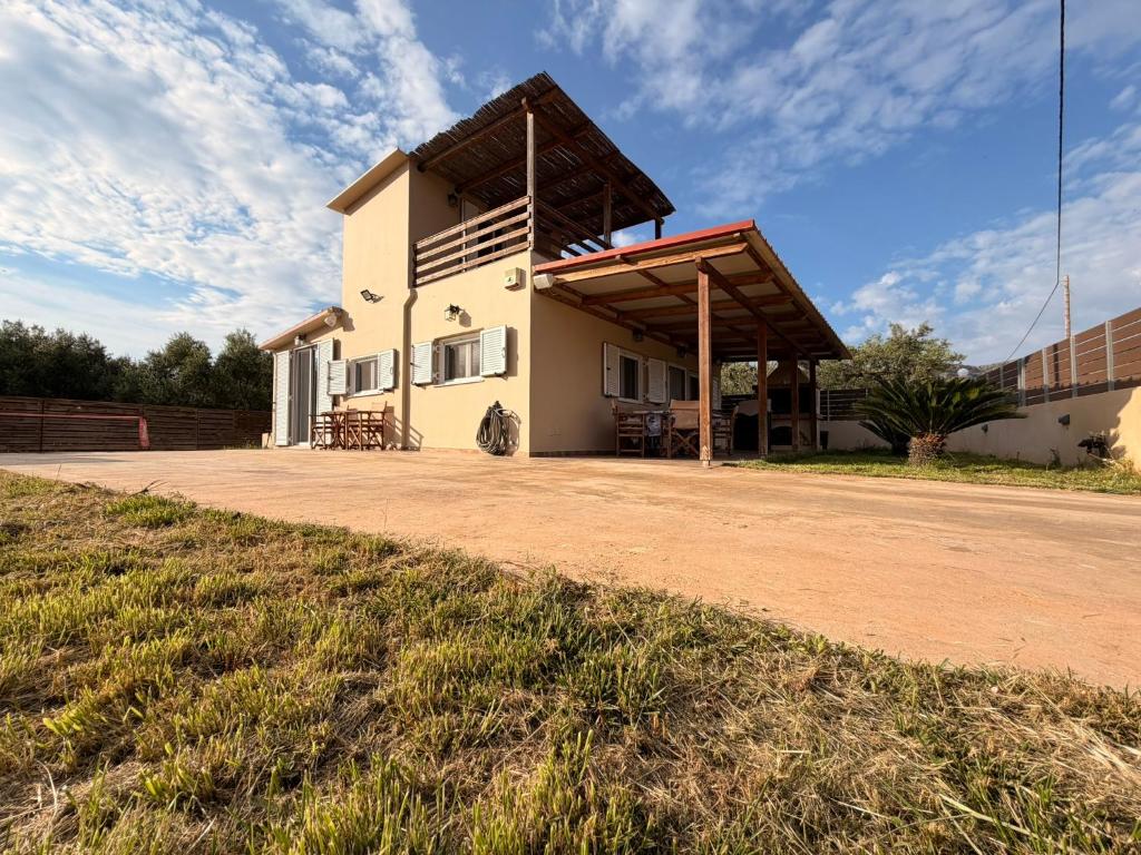 a white building with a roof on a dirt road at Villa Elena ΝΕΑΠΟΛΗ ΒΟΙΩΝ in Áyioi Apóstoloi