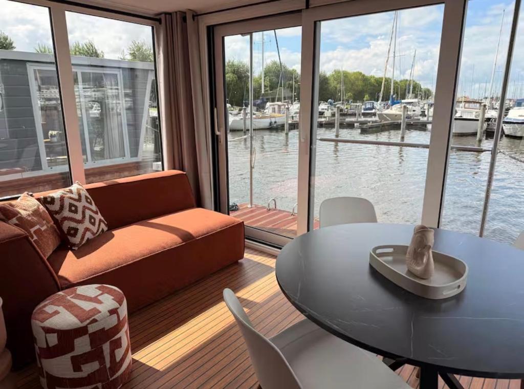 a living room with a couch and a table and a view of the water at Glamping Houseboat in Dinteloord