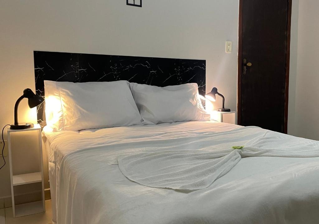 a bed with white sheets and pillows in a bedroom at 474 Flats e Suítes Standard in Ipatinga