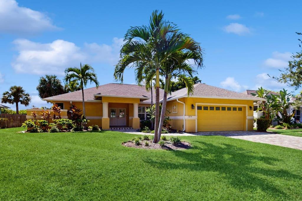 a yellow house with a palm tree in a yard at The Sunshine Social in Naples
