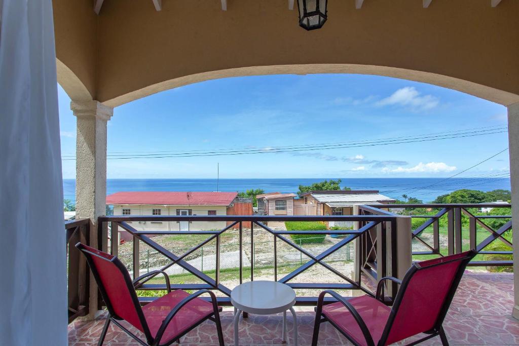 a balcony with chairs and a table and a view of the ocean at Oceanview Terrace, Walk to Beach, WiFi and Parking in Saint Lucy
