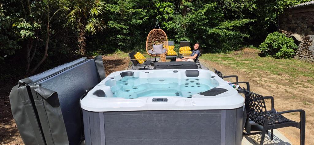 a man sitting in a hot tub in a yard at Manoir des Nobles Cœurs et Spa in Saint-Donan