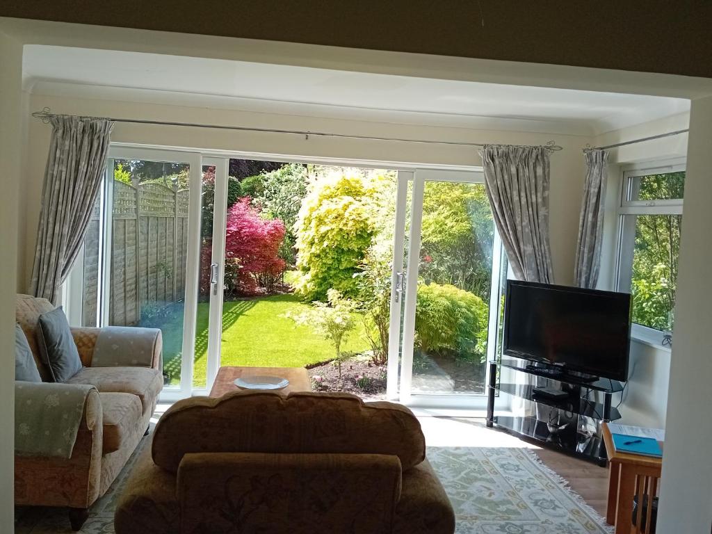 a living room with a tv and a large window at Abbeyside Cottage in Kelso