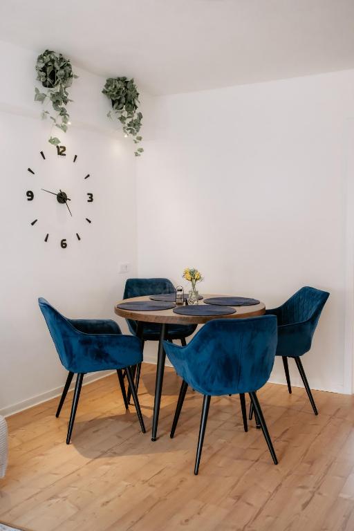 a dining room table with blue chairs and a clock on the wall at Apartment am Berg II in Grünstadt