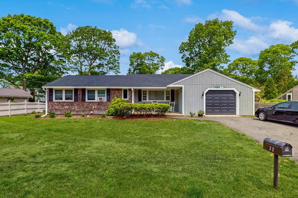 a house with a garage and a car parked in a yard at Great Pond Escape in Falmouth