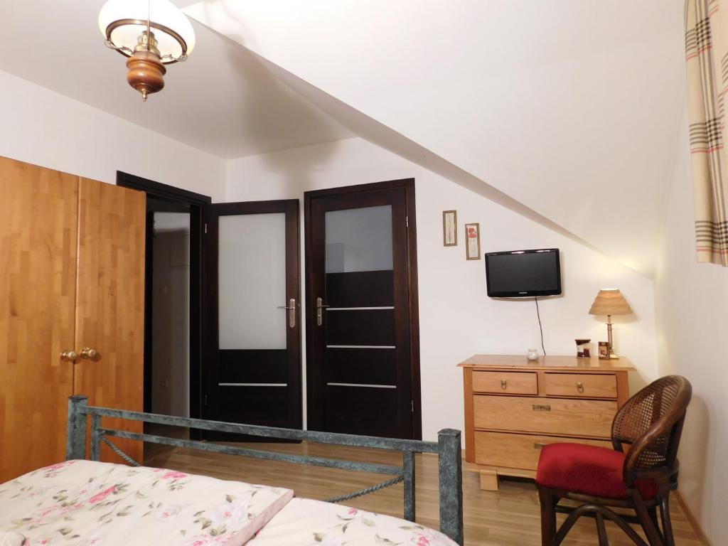 a bedroom with a bed and a dresser and a tv at Agroturystyka pod Czarną Sosną in Biały Ług