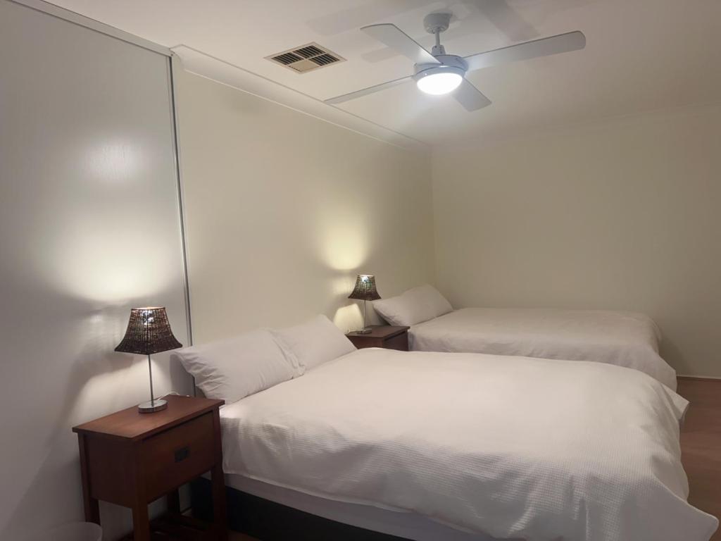 a bedroom with two beds and a ceiling fan at Private Room-2Queen beds in Elderslie