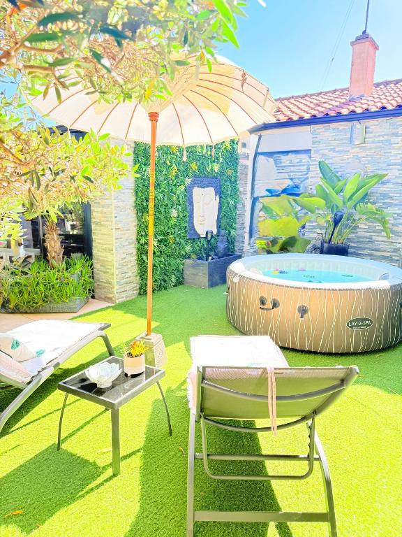 a patio with an umbrella and a table and a chair at O jardin des Sens -Séjour Bien-être & détente &Jacuzzi in Béziers