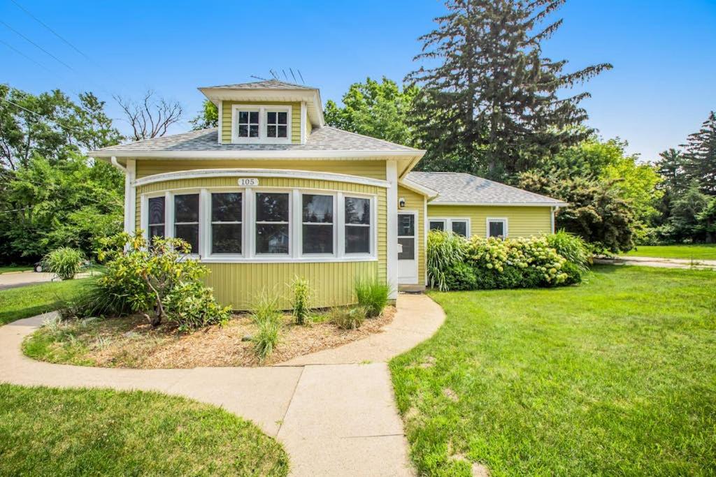 a yellow house with a lawn and a sidewalk at Hydrangea House in New Buffalo