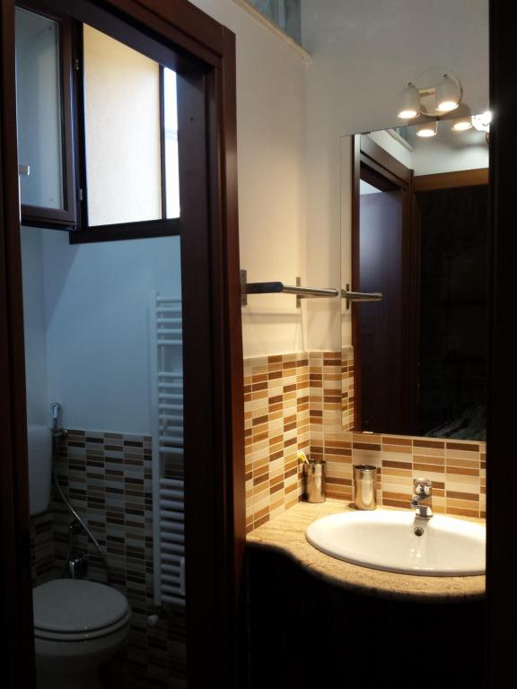 łazienka z umywalką, toaletą i lustrem w obiekcie Bed & Breakfast Via Venezia w mieście Regalbuto