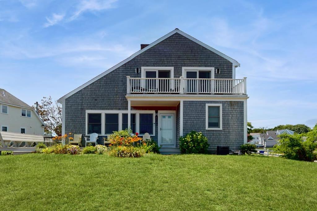 a house with a balcony on top of a yard at Harbor Point Cottage in Bourne