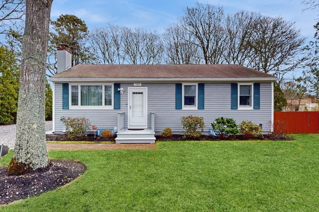 a blue and white house with a tree and grass at Hyannis Beach House in Hyannis