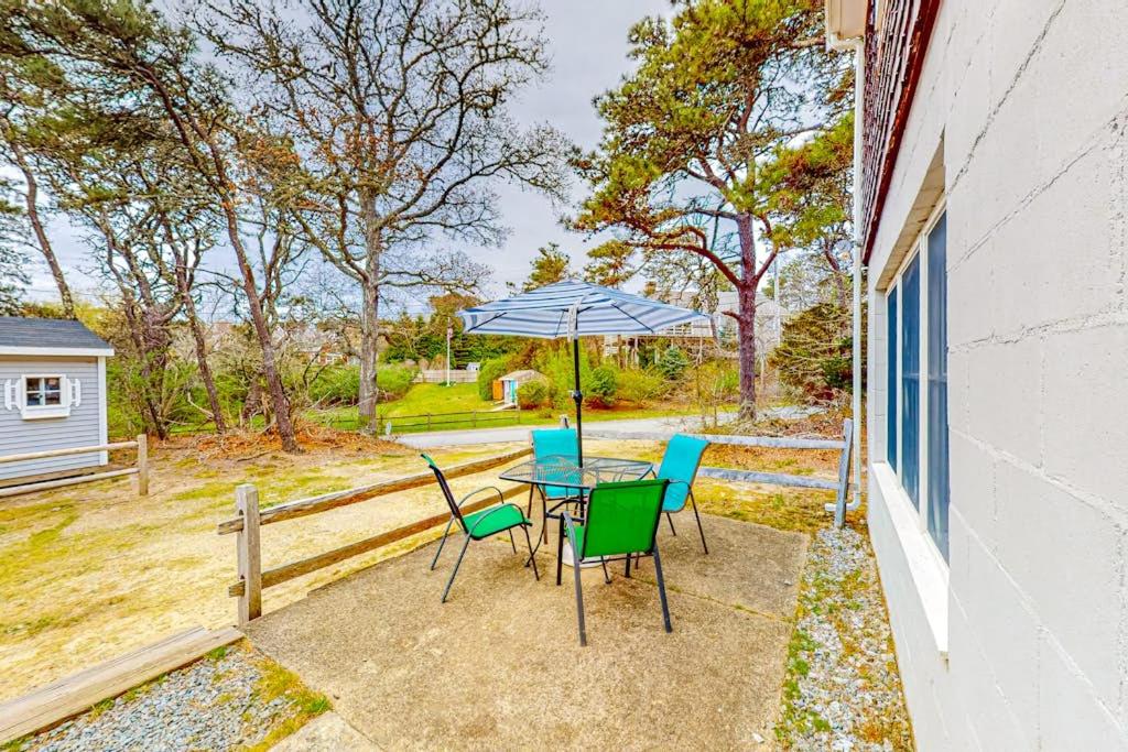 a patio with a table and chairs and an umbrella at Nauset Beach Buddy in Orleans