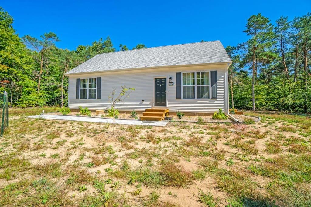 a small white house in the middle of a yard at Stay Awhile in Honor
