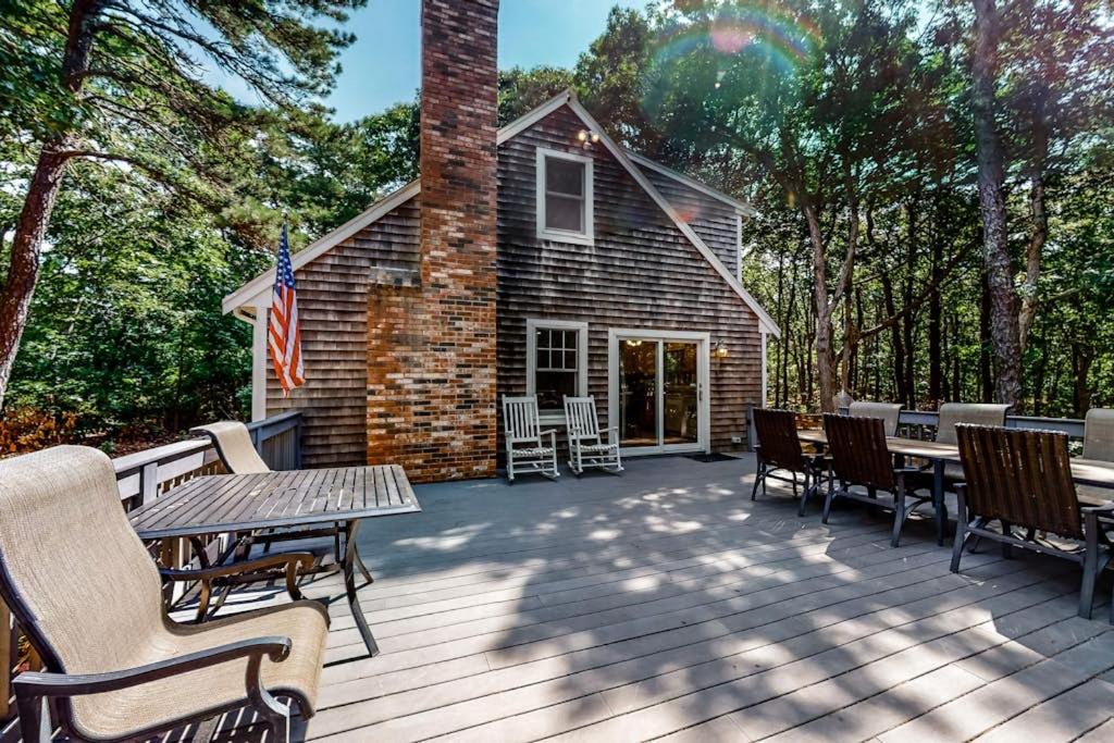 a deck with tables and chairs and a house at Lighthouse Lodge in Eastham