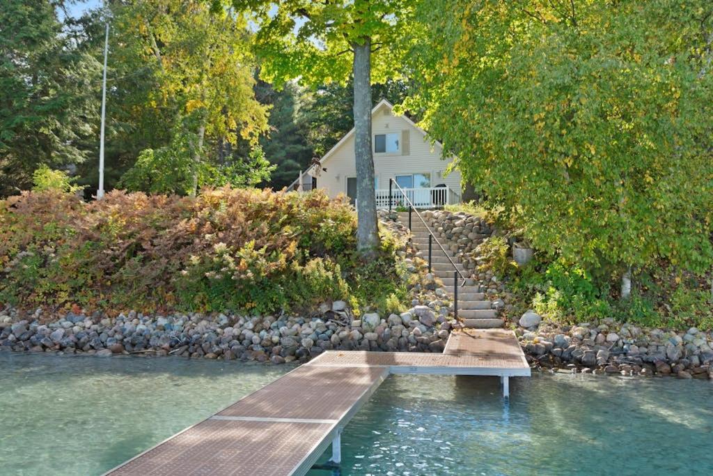 a dock in the water in front of a house at Walloon Lake Cottage in Boyne City