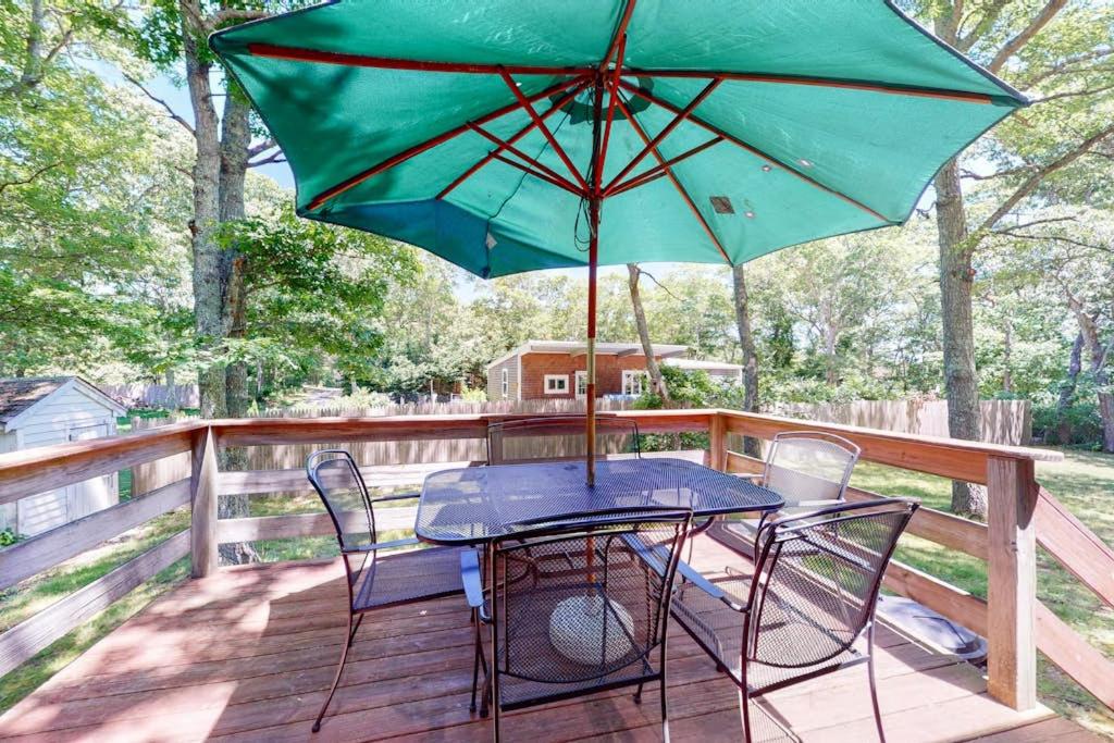 a table and chairs with a green umbrella on a deck at Sea Glen Cottage in Oak Bluffs