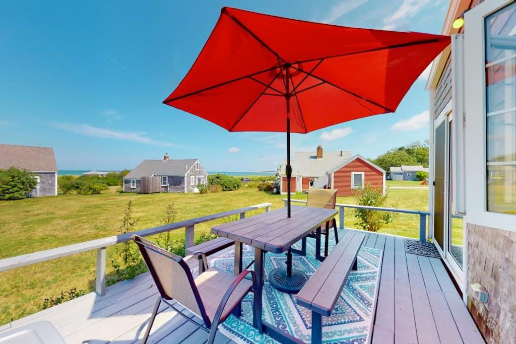 a picnic table with a red umbrella on a deck at Sea Coast Cottage in Barnstable